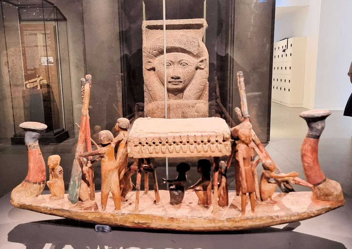 A model boat (reconstructed from several artifacts), with a column capital depicting Hathor behind Chau Chak Wing Museum Sydney